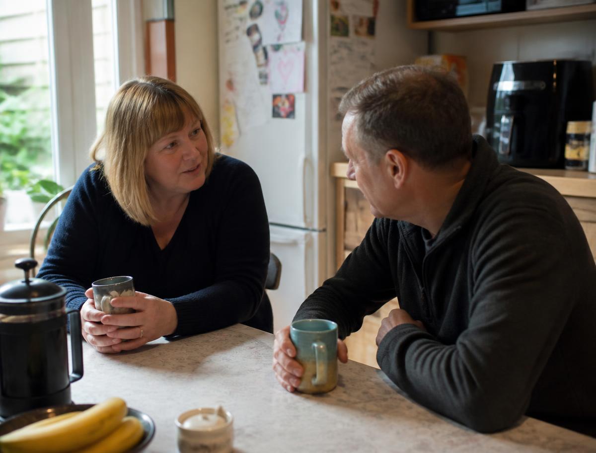 A support worker and a resident talking over a cup of tea at a kitchen table
